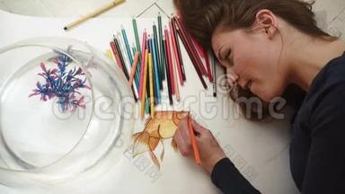 可爱的年轻女艺术家画了一幅小金鱼特写的照片。 顶部视图